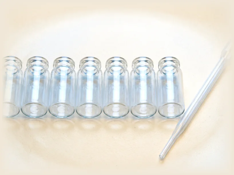 A row of plain clear glass vials beside a glass pipette