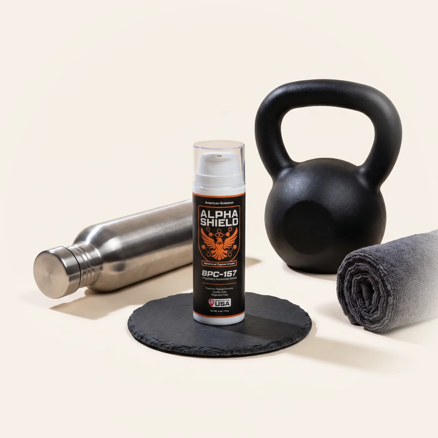 Alpha Shield on a slate coaster with a kettlebell, steel bottle and rolled towel